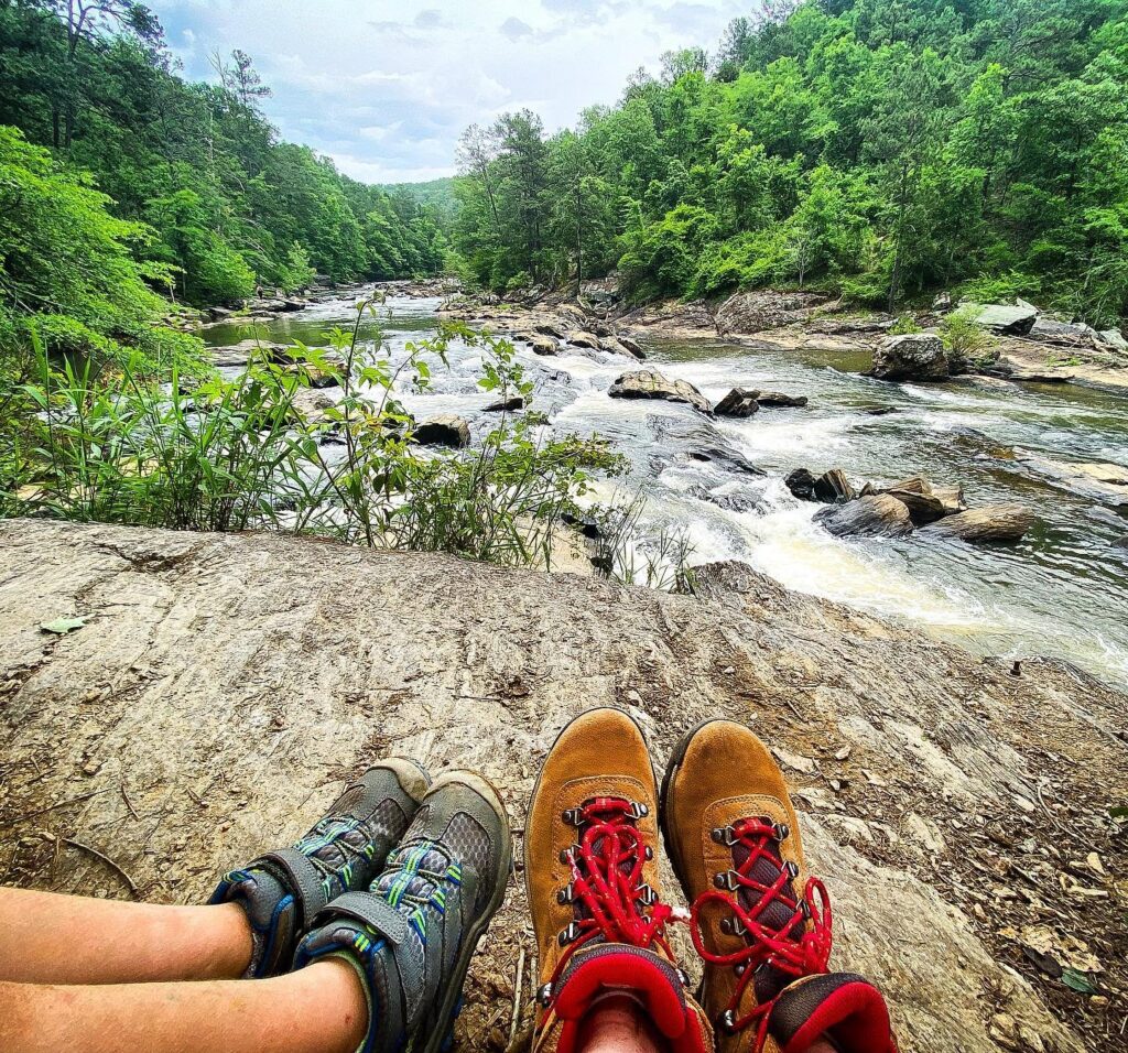 Photo of feet in shoes resting on rock watching Sweetwater Creek in Douglasville, GA